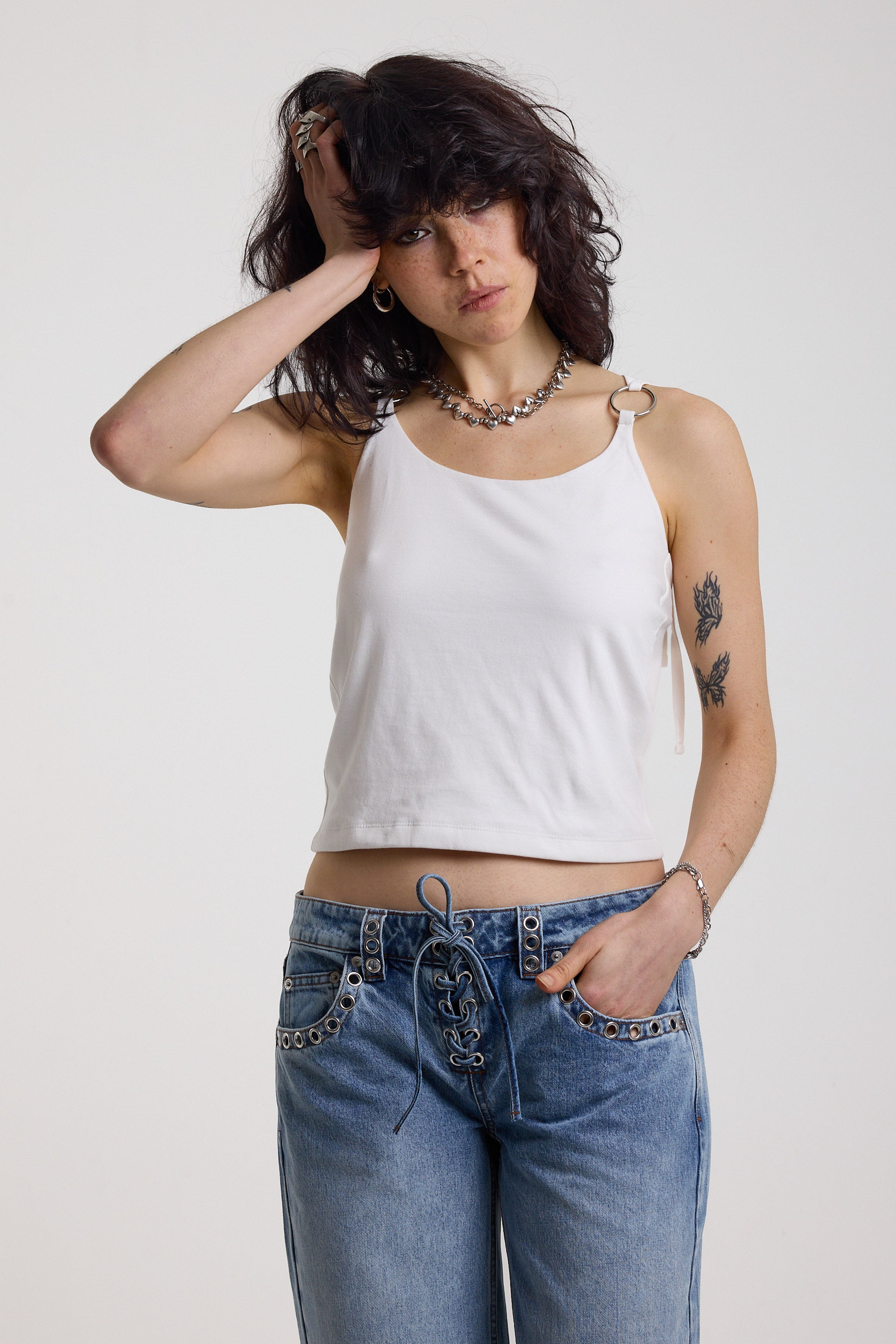 White strappy cami top with tie straps, cowl back and silver O rings, worn by model