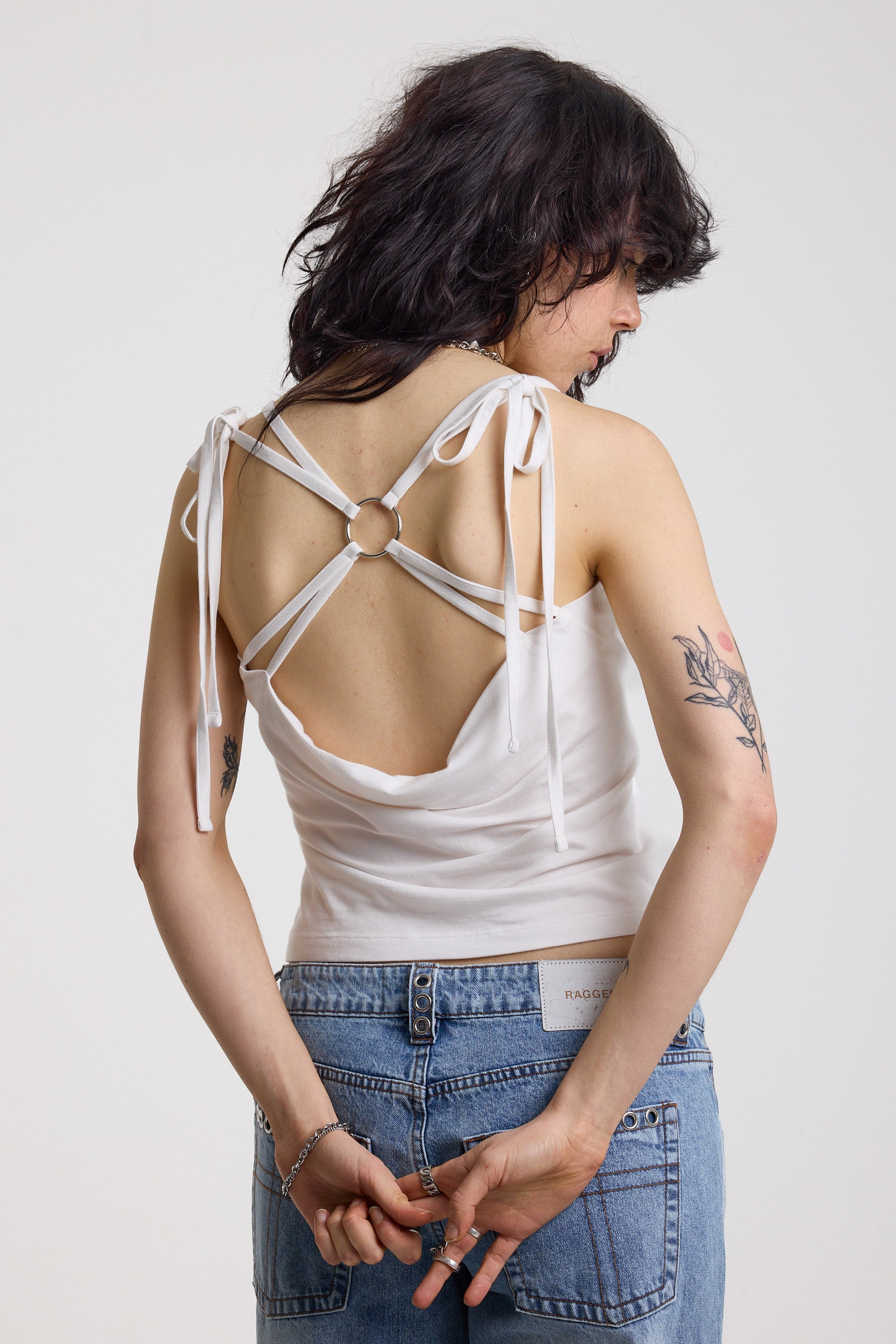 White strappy cami top with tie straps, cowl back and silver O rings, worn by model