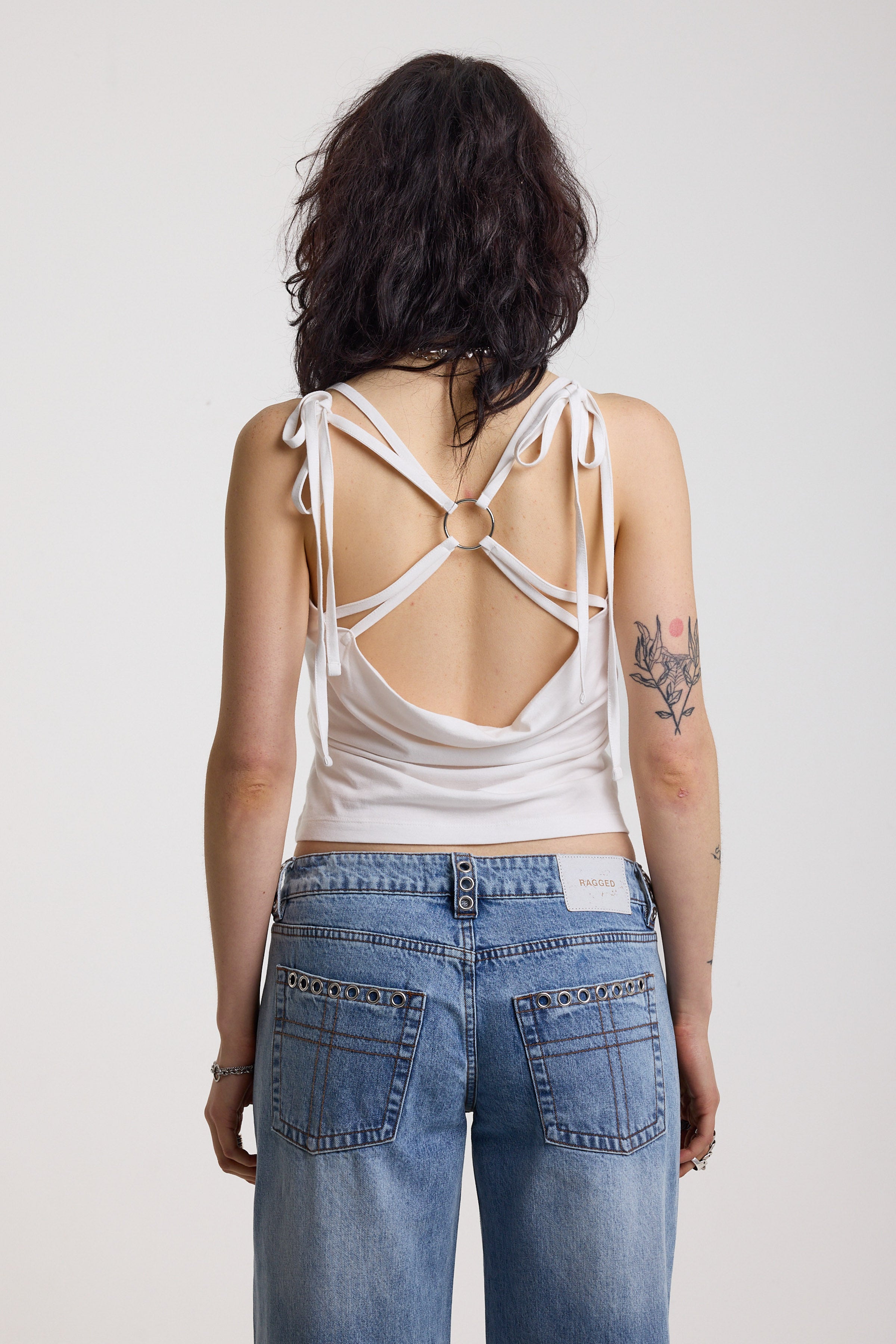 White strappy cami top with tie straps, cowl back and silver O rings, worn by model