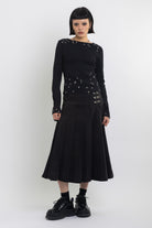Black denim pleated midi skirt with silver clasp hardware, worn by model