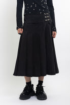 Black denim pleated midi skirt with silver clasp hardware, worn by model