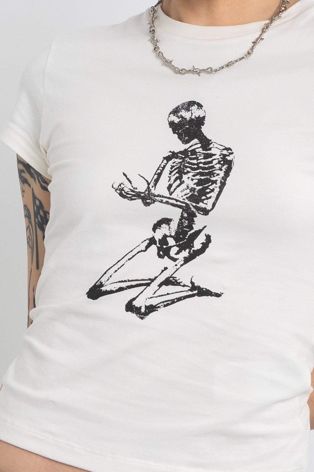 Off white baby t-shirt with praying skeleton graphic print, worn by model