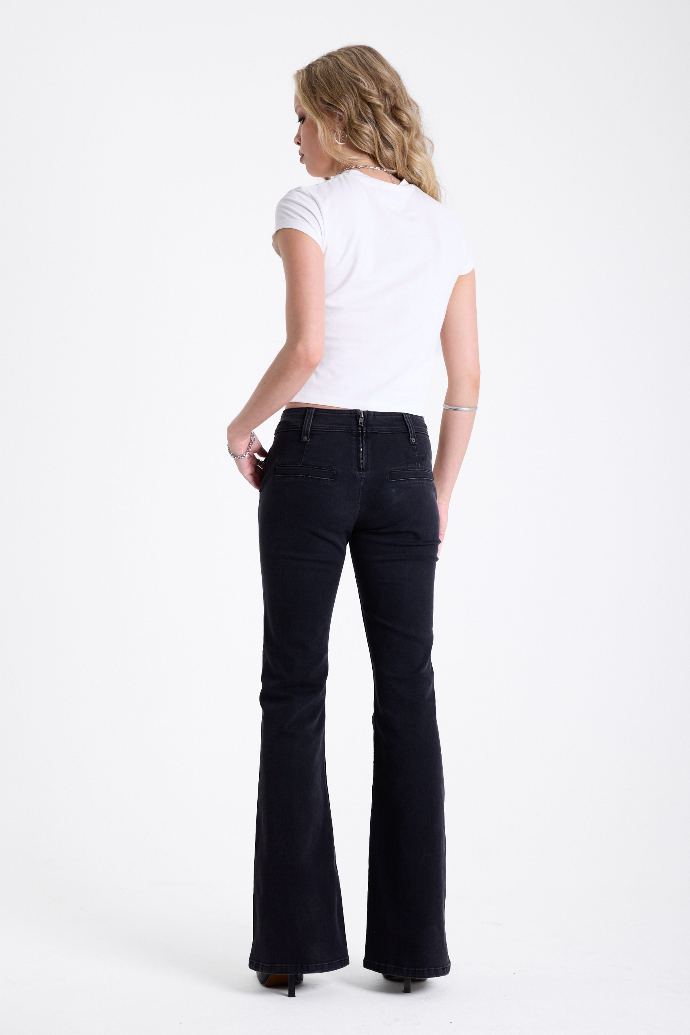 Washed black seam detail flare jeans with studs at waistband and back zip, worn by model. 