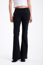 Washed black seam detail flare jeans with studs at waistband and back zip, worn by model. 