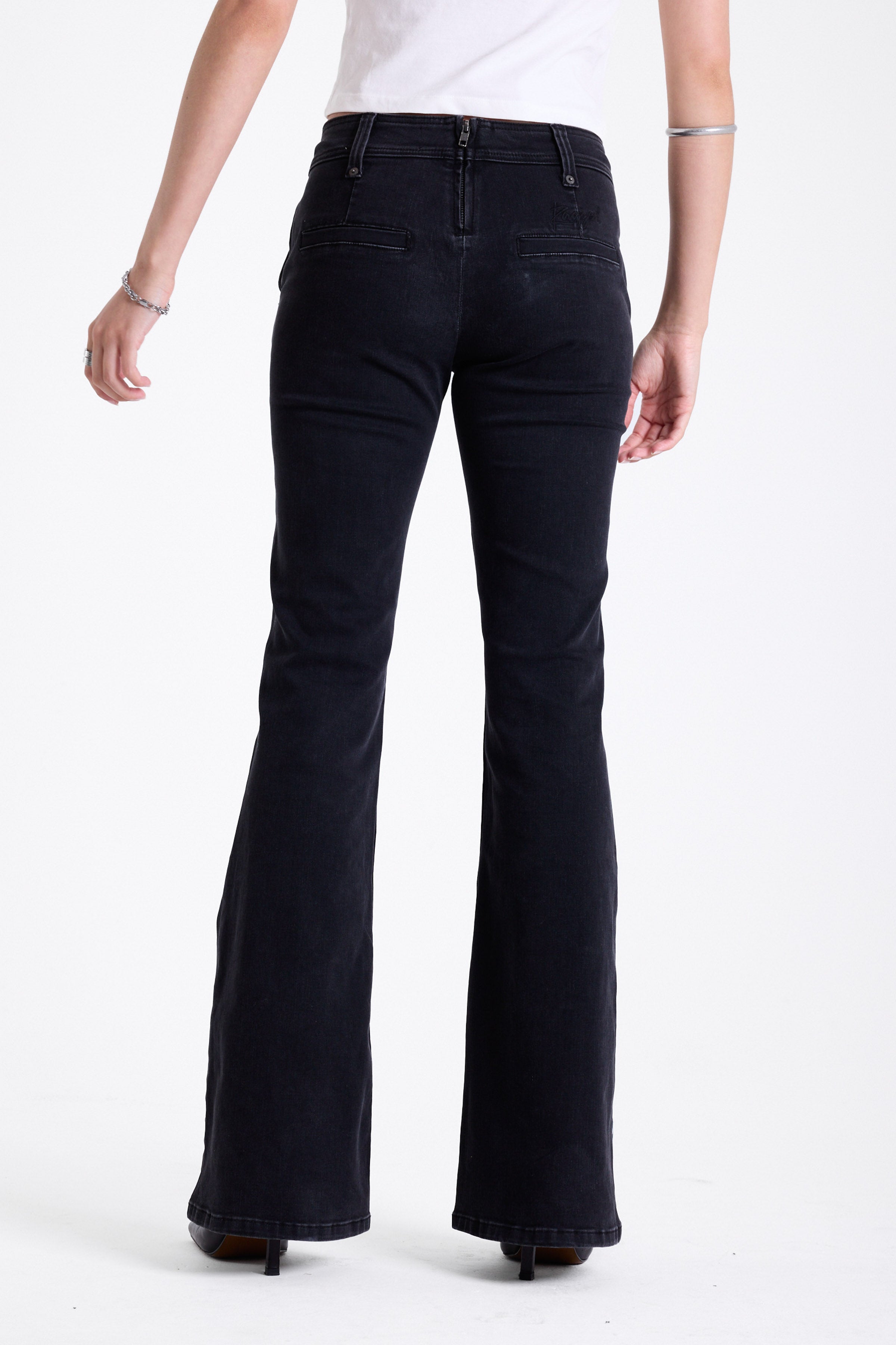 Washed black seam detail flare jeans with studs at waistband and back zip, worn by model. 