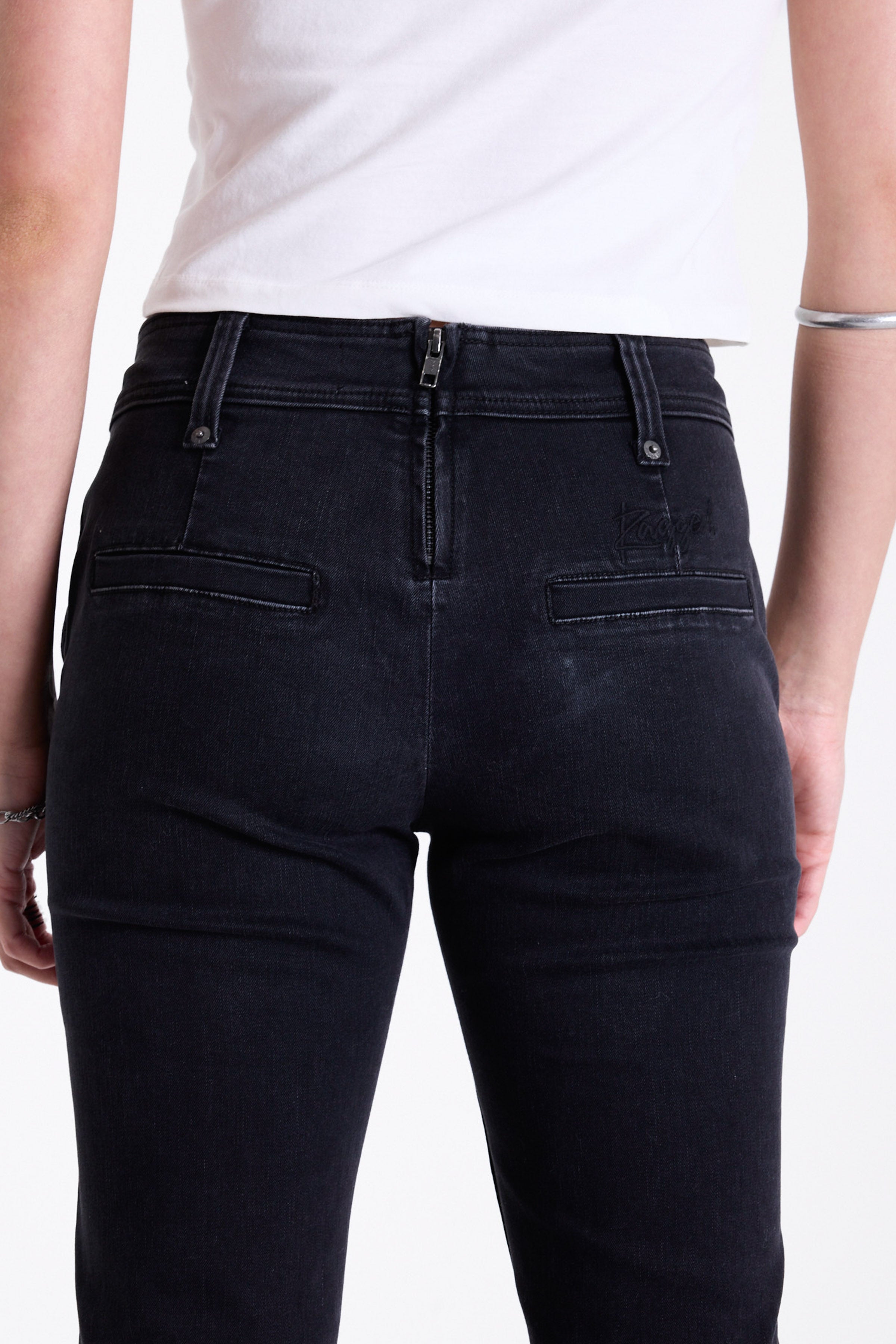 Washed black seam detail flare jeans with studs at waistband and back zip, worn by model. 