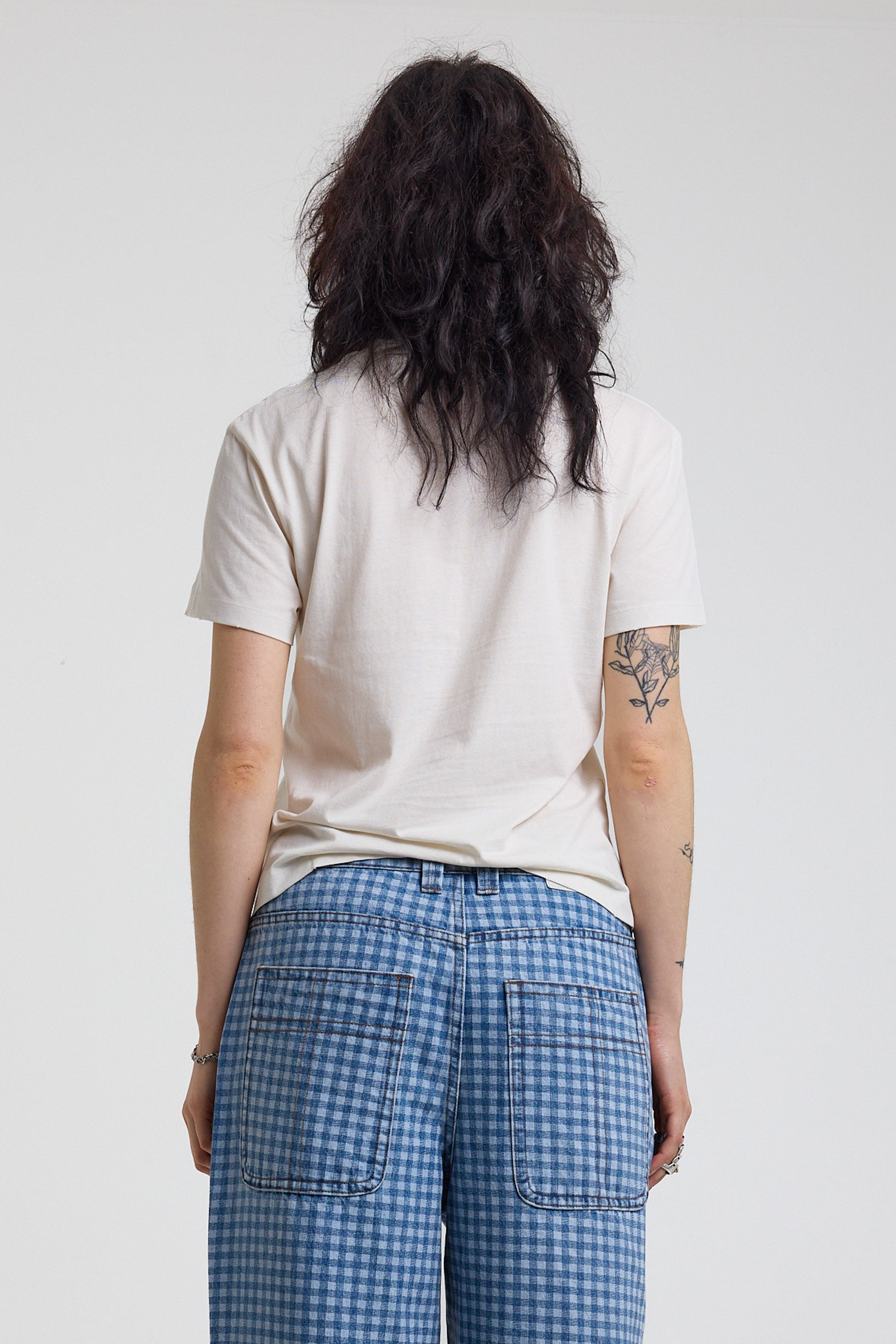 Back image of white shrunken baby t-shirt with vintage angel graphic print, worn by a model