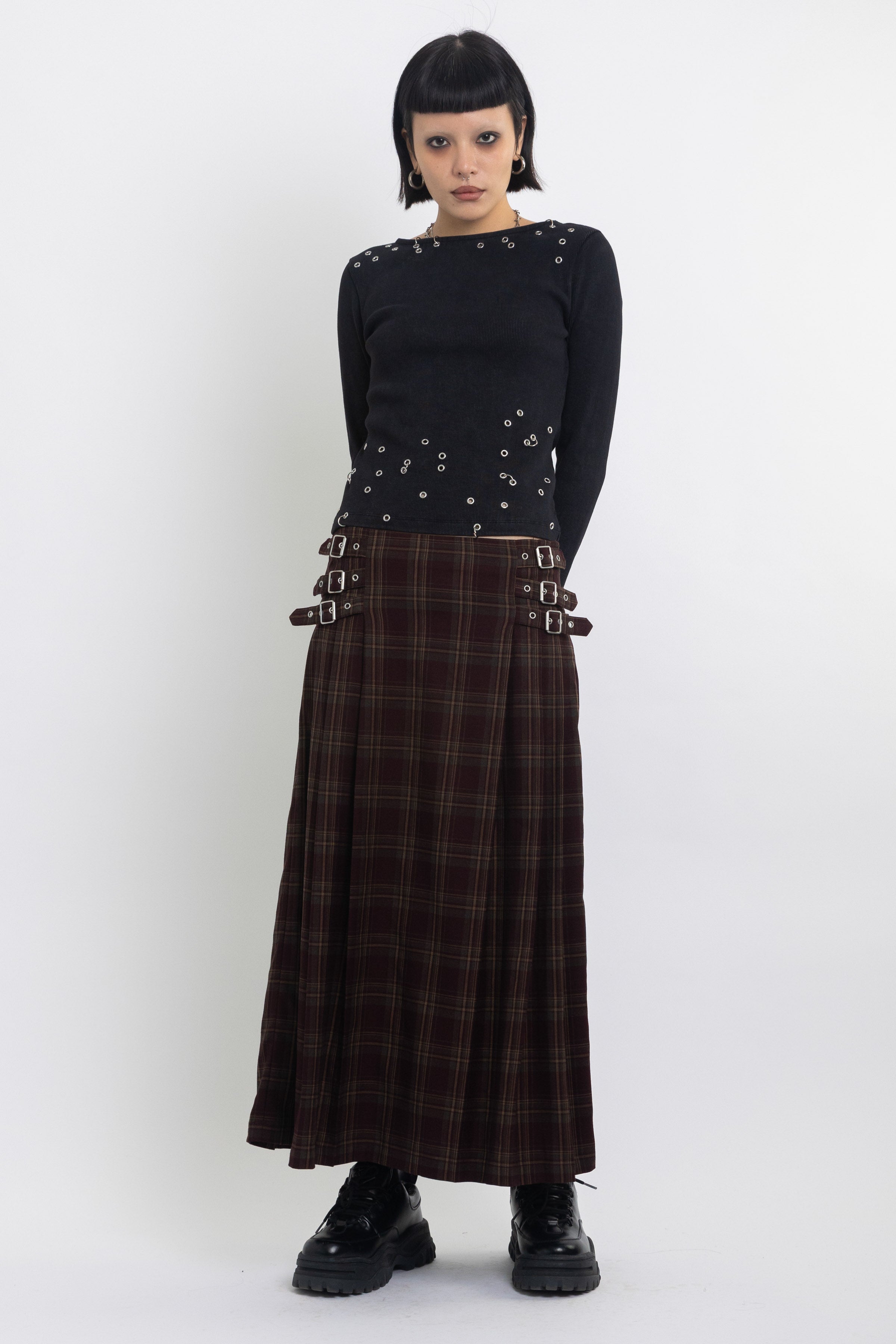 Burgundy check kilt style maxi skirt with silver buckles at the side, worn by model