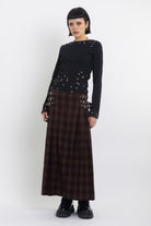 Burgundy check kilt style maxi skirt with silver buckles at the side, worn by model