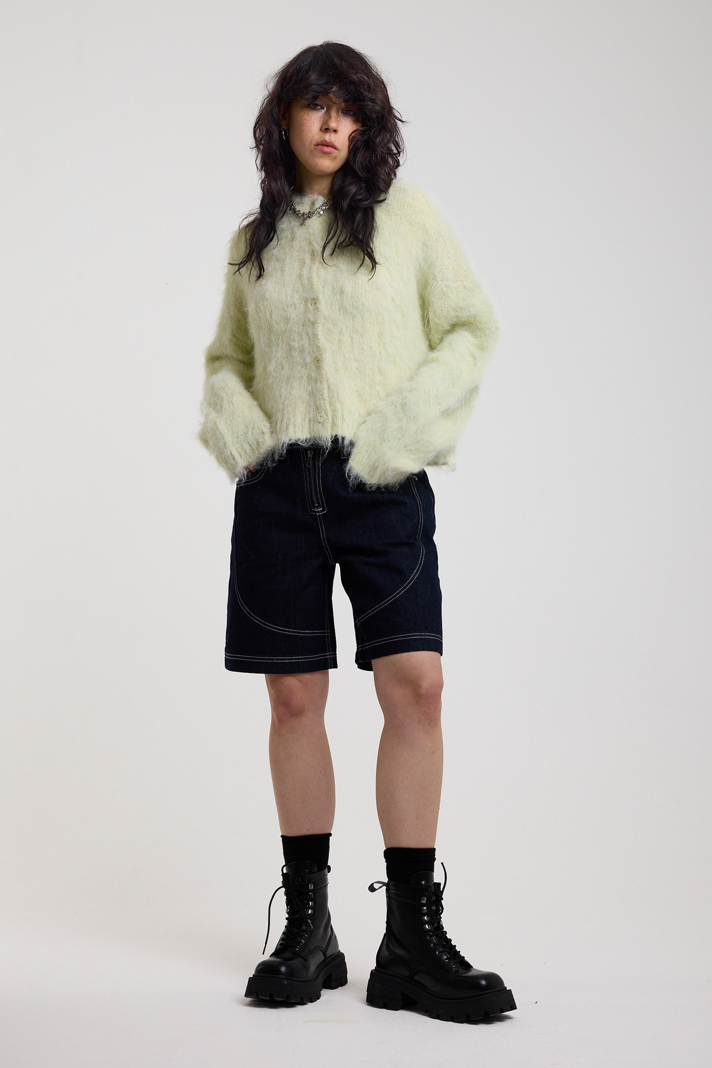 Pale green fuzzy knit cardigan with gothic Baby slogan on back, worn by model