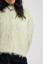 Close up showing fuzzy fluffy knit on ale green cardigan with gothic Baby slogan on back, worn by model