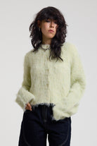 Pale green fuzzy knit cardigan with gothic Baby slogan on back, worn by model