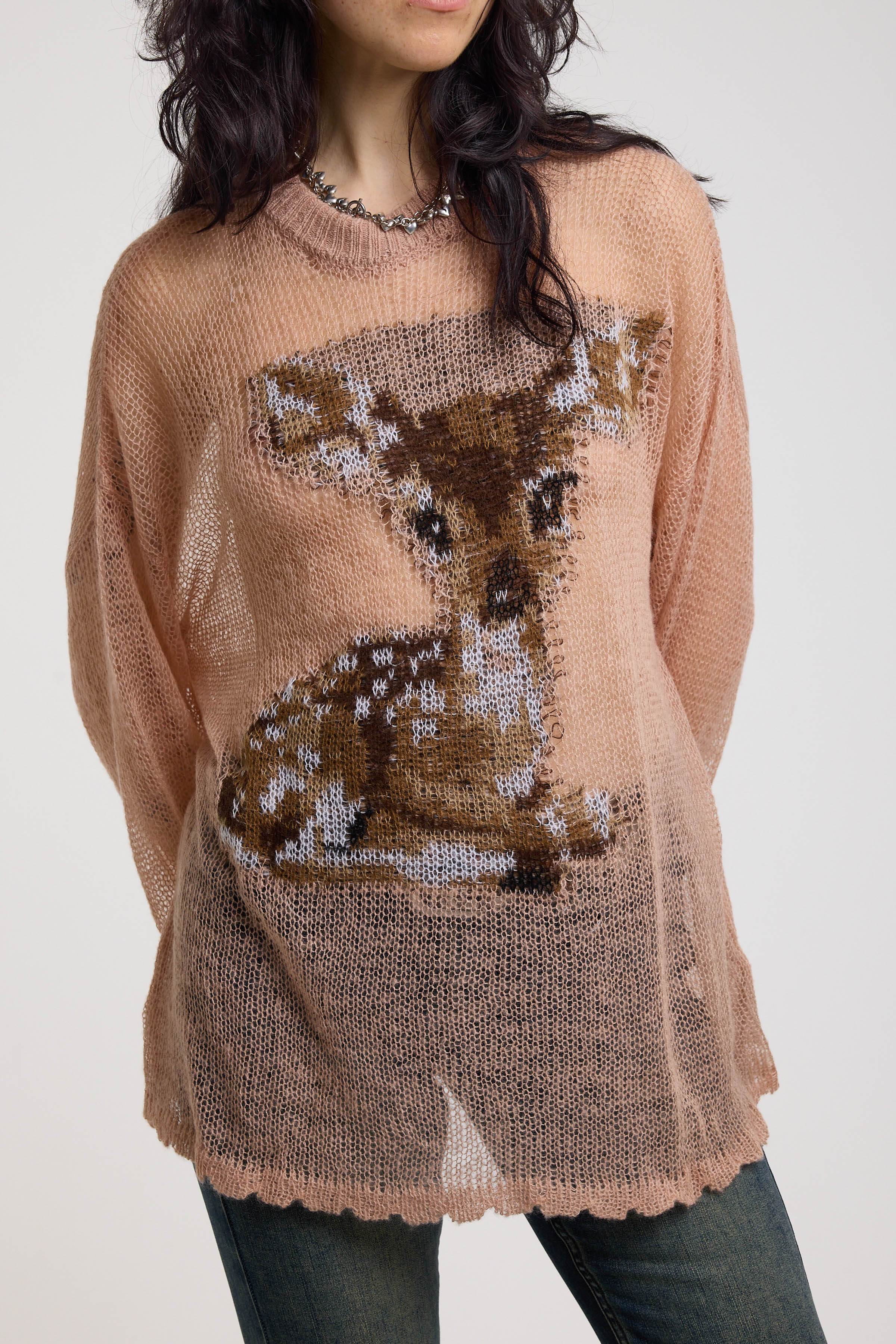 Close up detail of deer graphic on dusty pink oversized sheer open knit jumper, worn by model