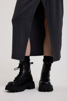 Split hem on charcoal plunging wrap dress with silver hardware clasps and D-ring strap detail, worn by model