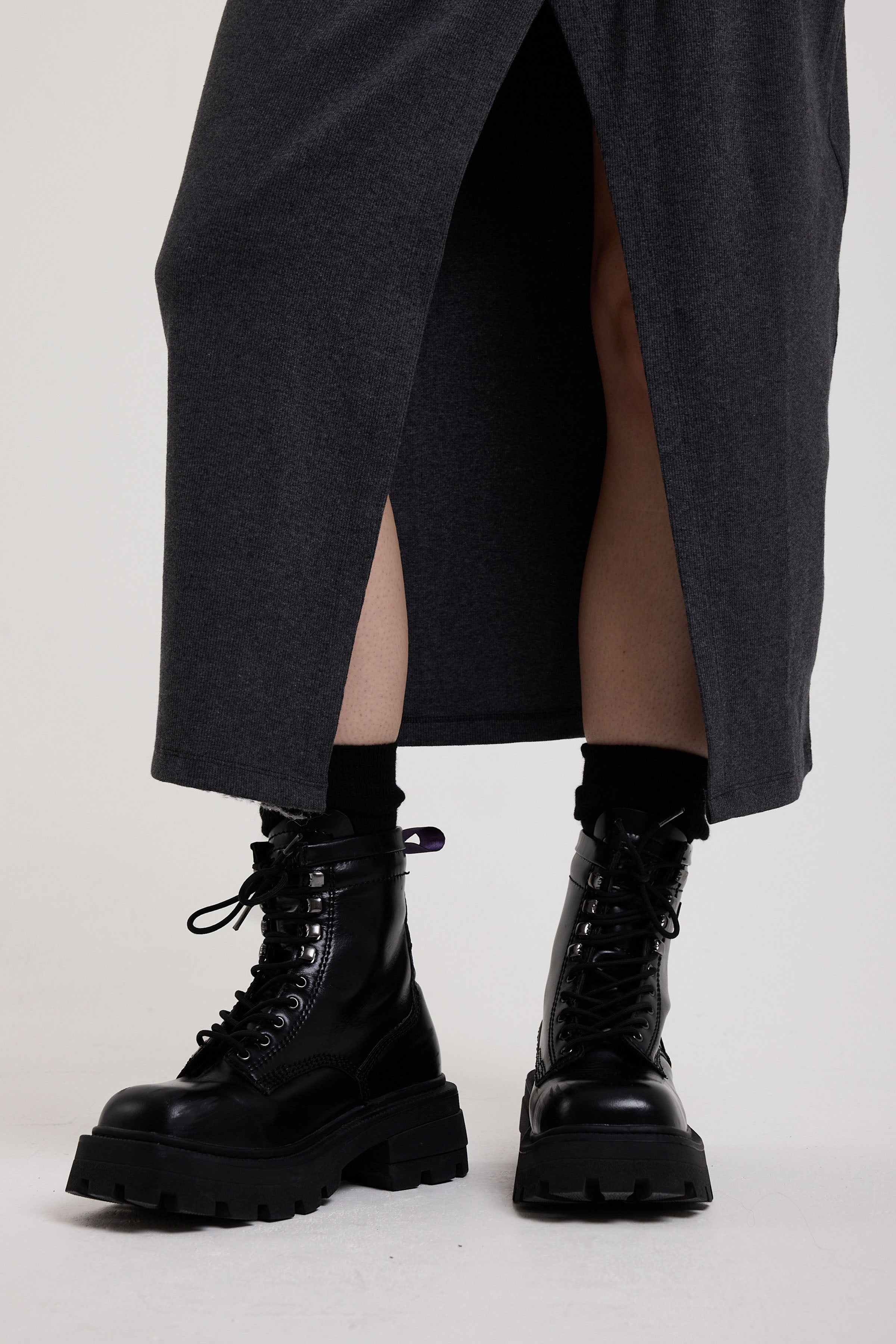 Split hem on charcoal plunging wrap dress with silver hardware clasps and D-ring strap detail, worn by model