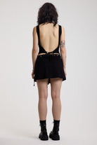 Black eyelet detail mini wrap skirt with adjustable ties, worn by model