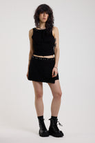 Black slash neck open back tank top with silver eyelet detail, worn by model