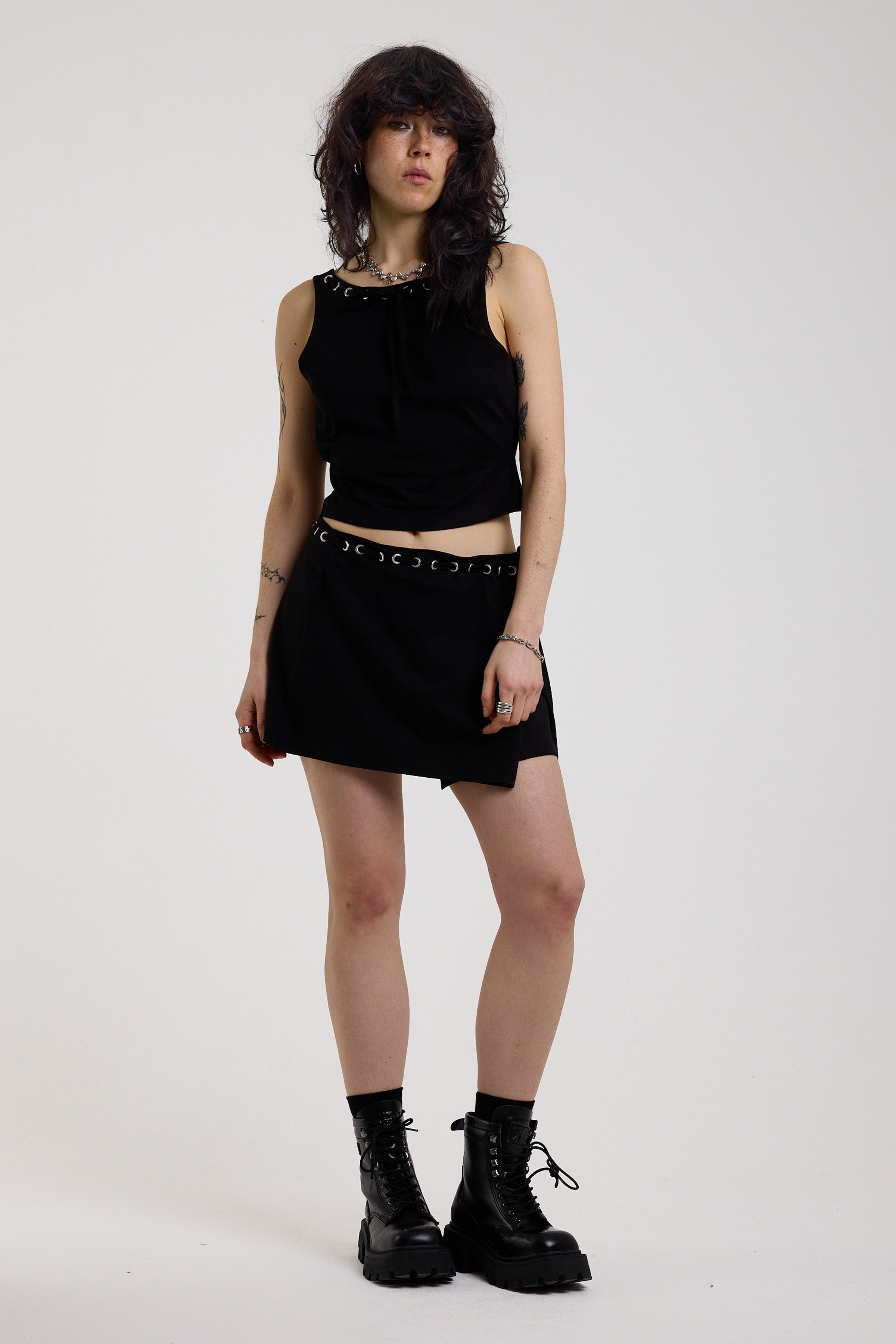 Black eyelet detail mini wrap skirt with adjustable ties, worn by model