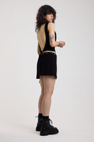 Black slash neck open back tank top with silver eyelet detail and matching mini wrap skirt, worn by model