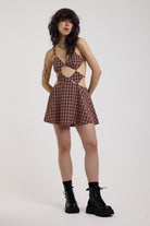 Grunge burgundy check strappy mini dress with cut out panels, silver hardware and tie back detail, worn by model