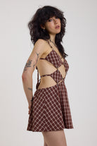 Grunge burgundy check strappy mini dress with cut out panels, silver hardware and tie back detail, worn by model