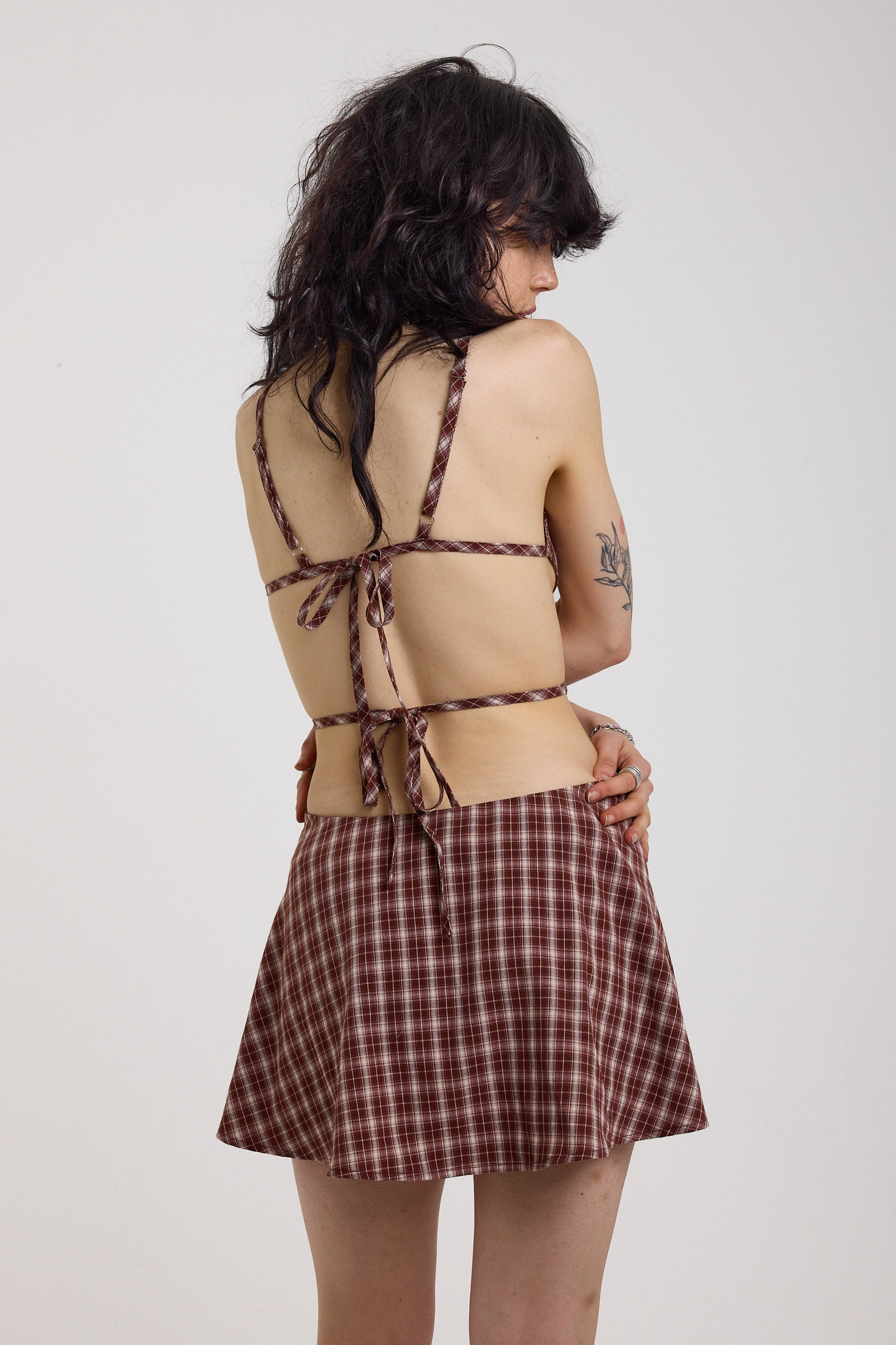 Grunge burgundy check strappy mini dress with cut out panels, silver hardware and tie back detail, worn by model