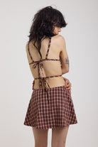Grunge burgundy check strappy mini dress with cut out panels, silver hardware and tie back detail, worn by model