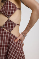 Grunge burgundy check strappy mini dress with cut out panels, silver hardware and tie back detail, worn by model