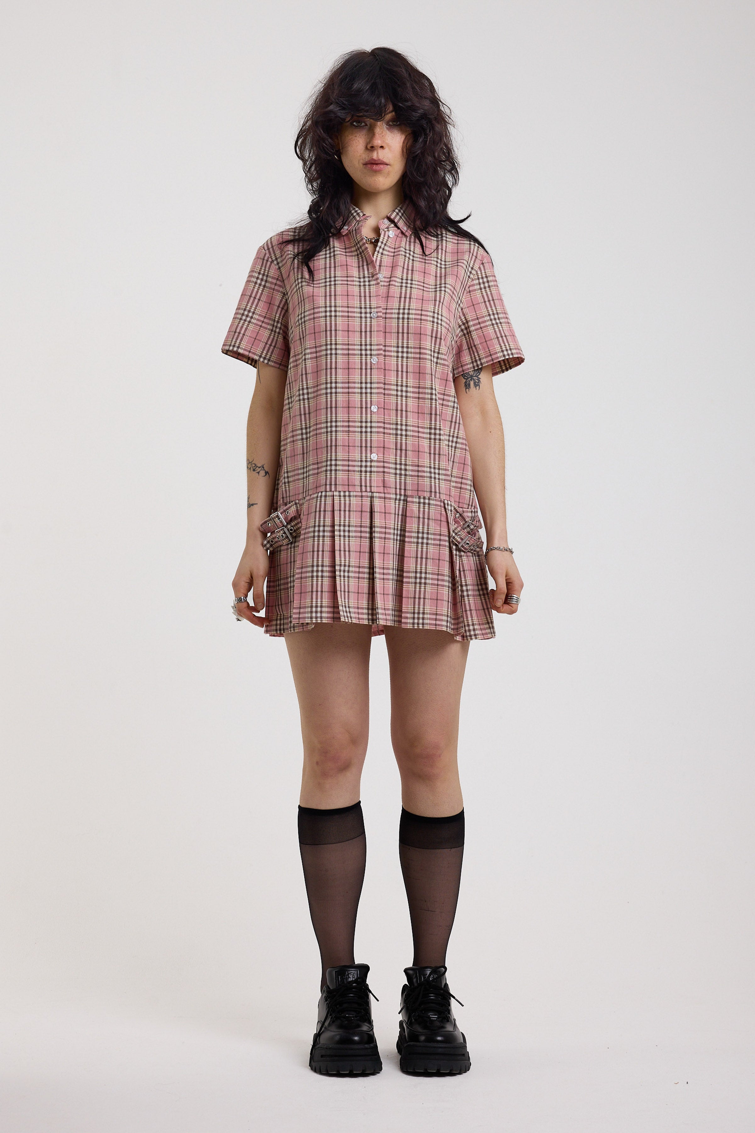 Pink tartan check mini dress with pleated mini skirt buttons, collar and silver buckle detail, worn by model