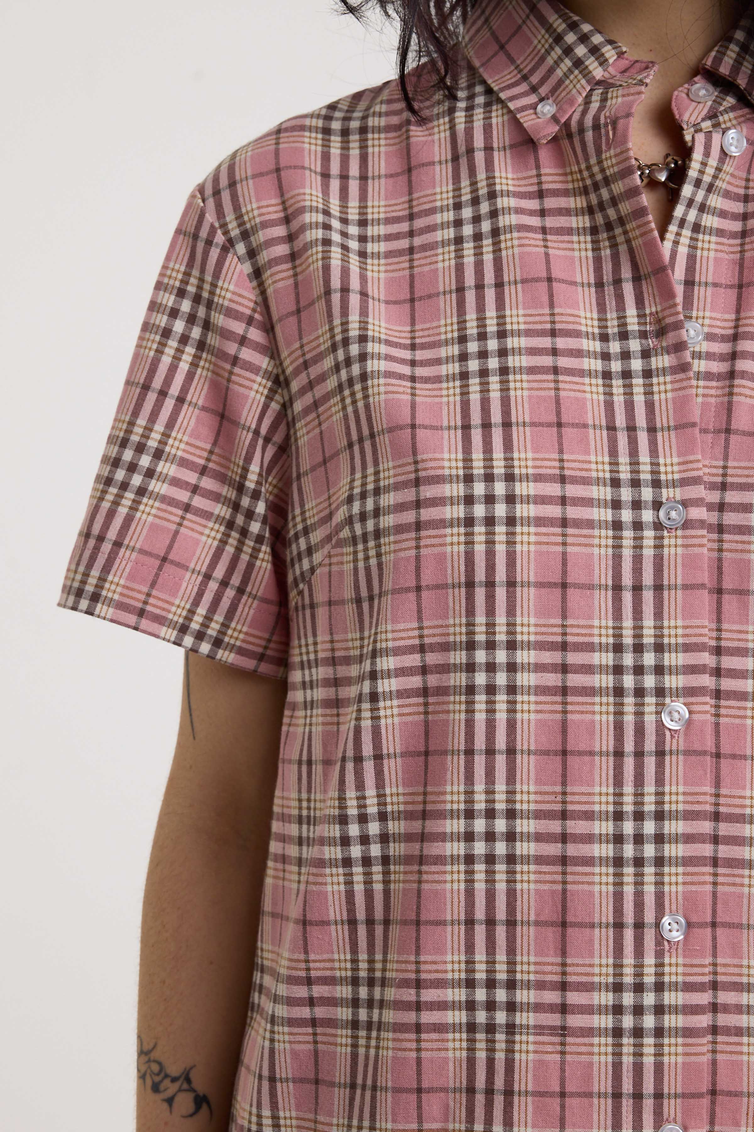 Close up of pink tartan check, short sleeves and button down collar on mini dress, worn by model