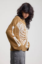 Brown oversized knit jumper with skeleton graphic, worn by model