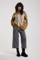 Brown oversized knit jumper with skeleton graphic, worn by model