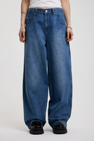 Dark blue ultra baggy wide leg jeans with hardware eyelet detail cinch back belt, worn by model