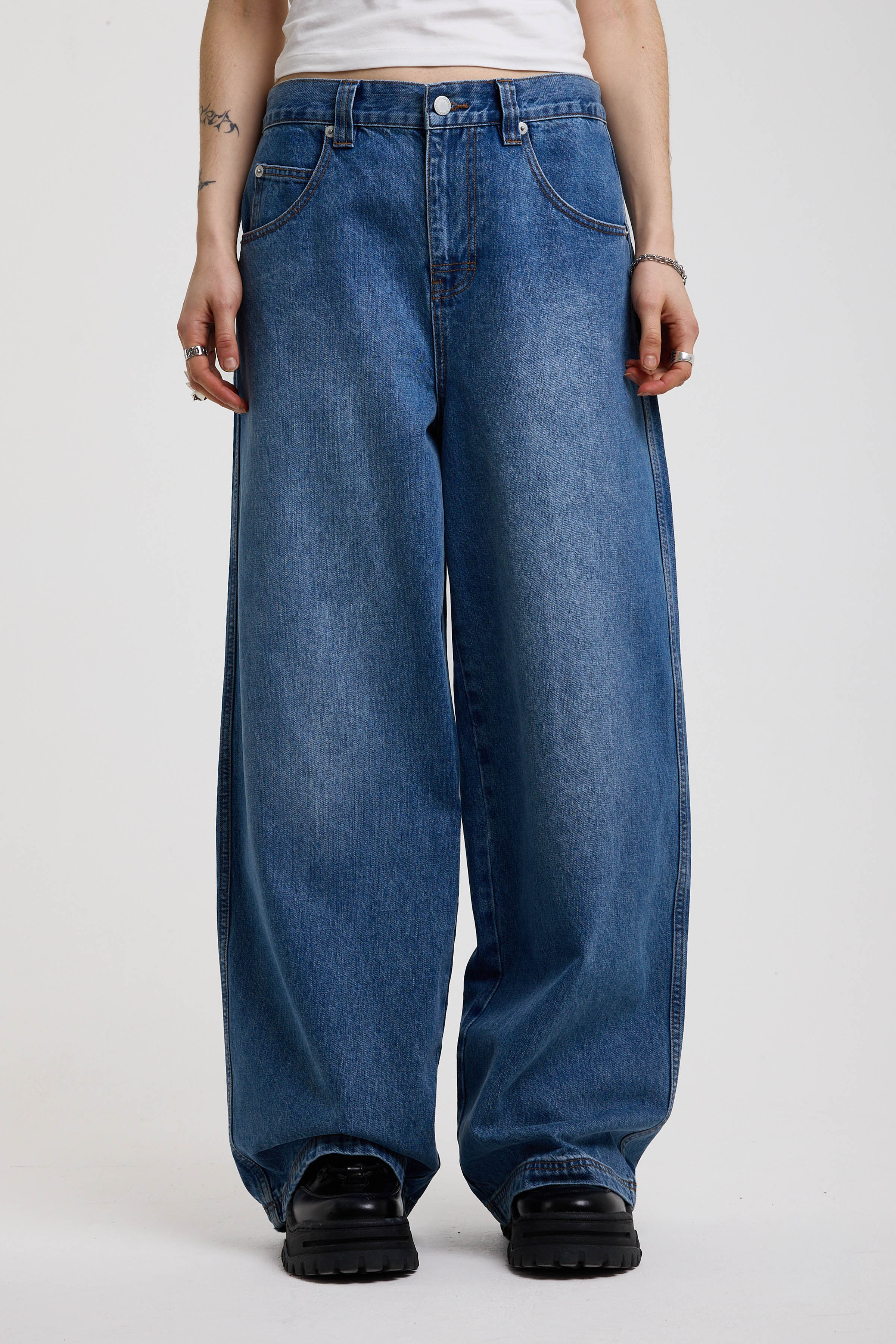 Dark blue ultra baggy wide leg jeans with hardware eyelet detail cinch back belt, worn by model