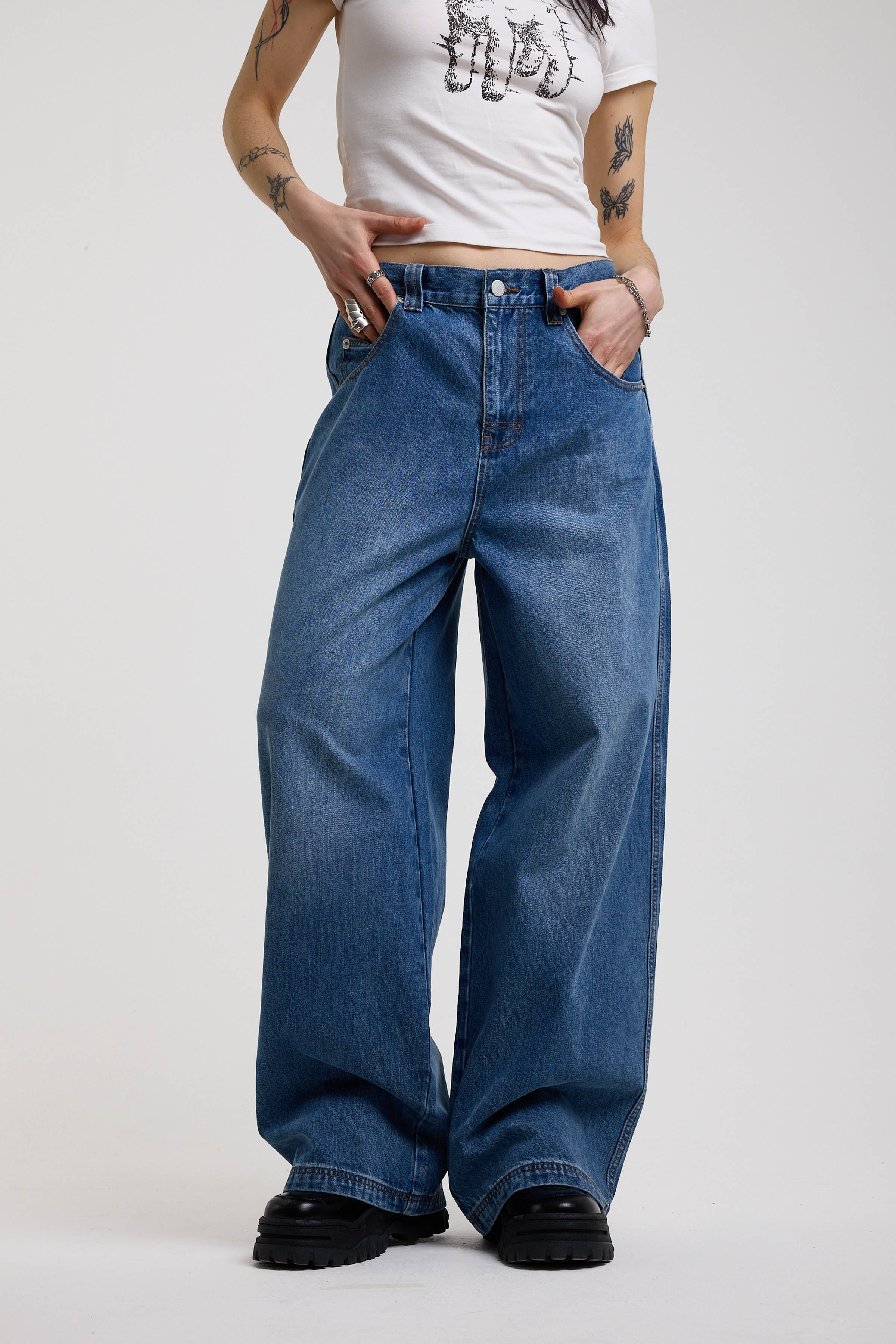 Dark blue ultra baggy wide leg jeans with hardware eyelet detail cinch back belt, worn by model