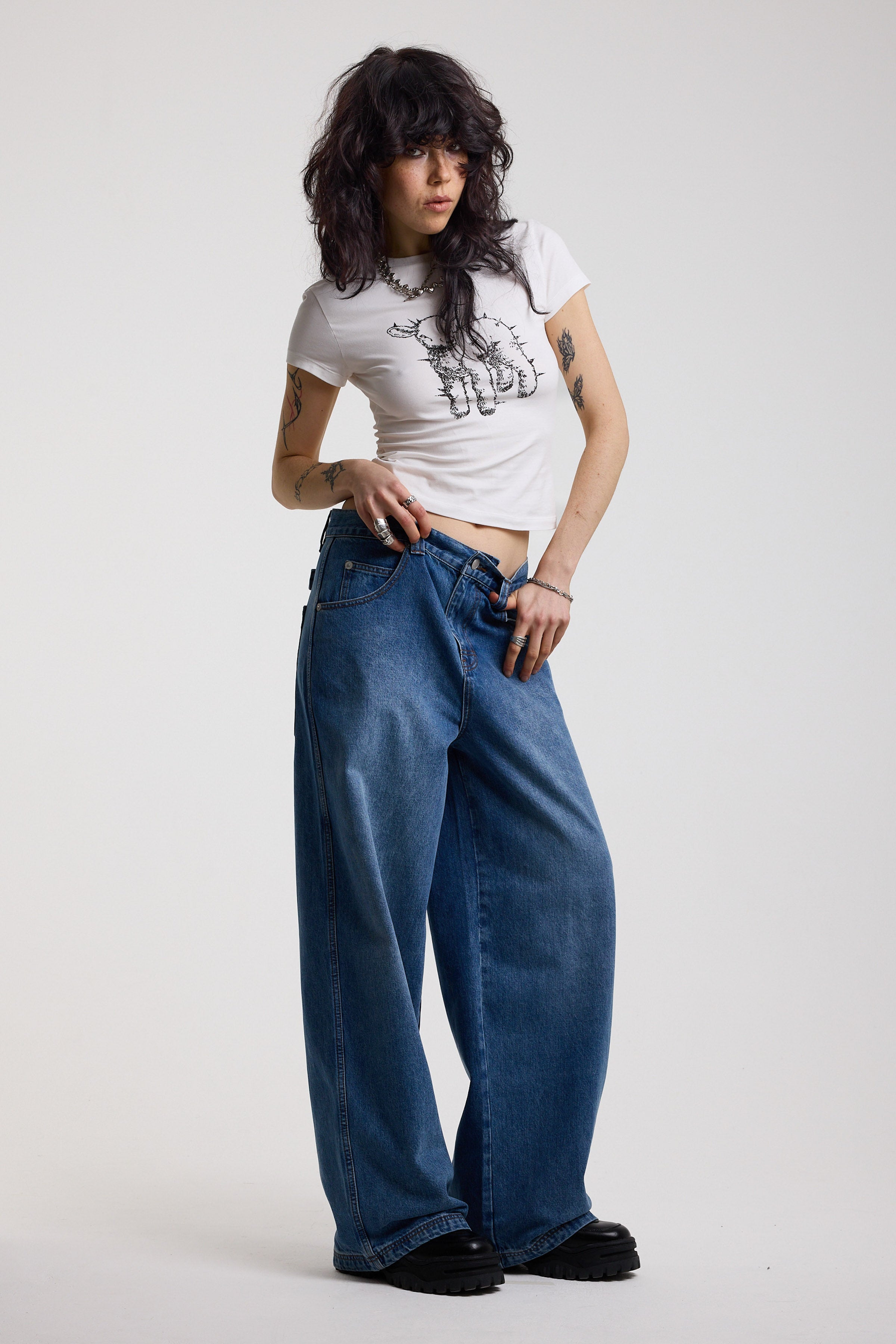 Dark blue ultra baggy wide leg jeans with hardware eyelet detail cinch back belt, worn by model