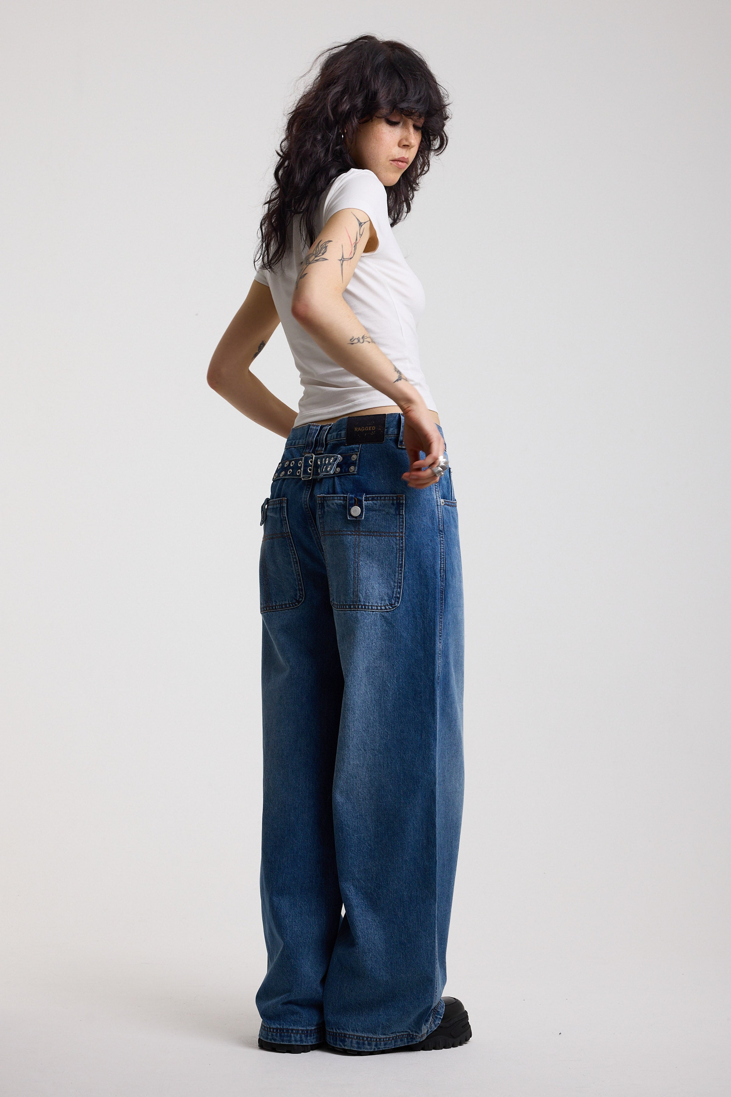 Dark blue ultra baggy wide leg jeans with hardware eyelet detail cinch back belt, worn by model