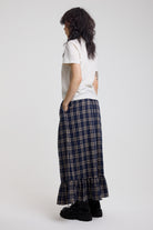 Side image of blue and yellow check maxi skirt with peplum hem showing pocket detail, worn by model