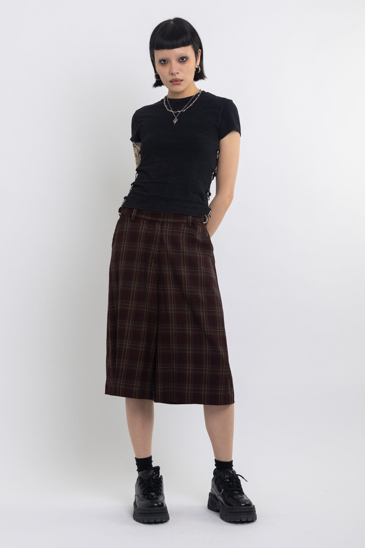 Burgundy check longline tailored shorts with silver D-ring hardware worn by model
