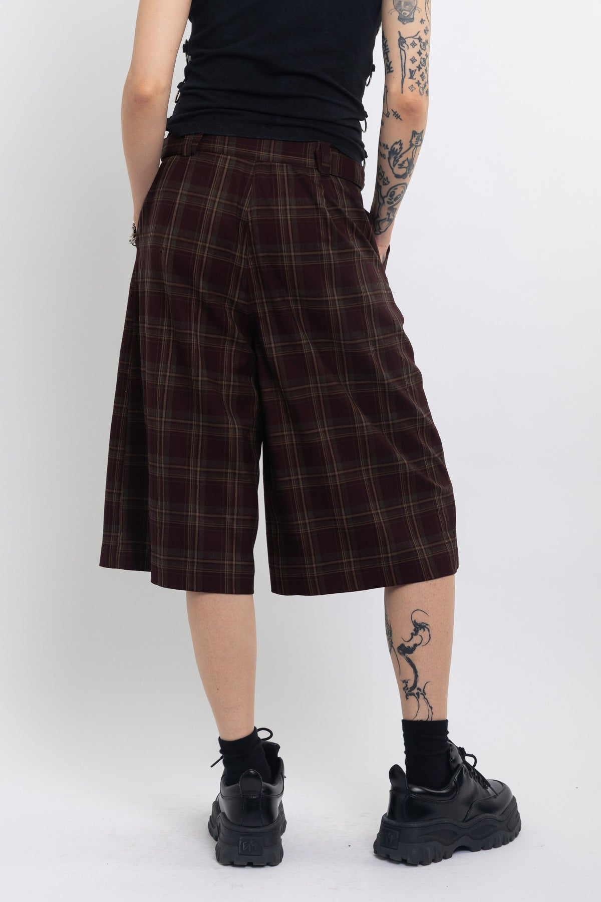 Burgundy check longline tailored shorts with silver D-ring hardware worn by model