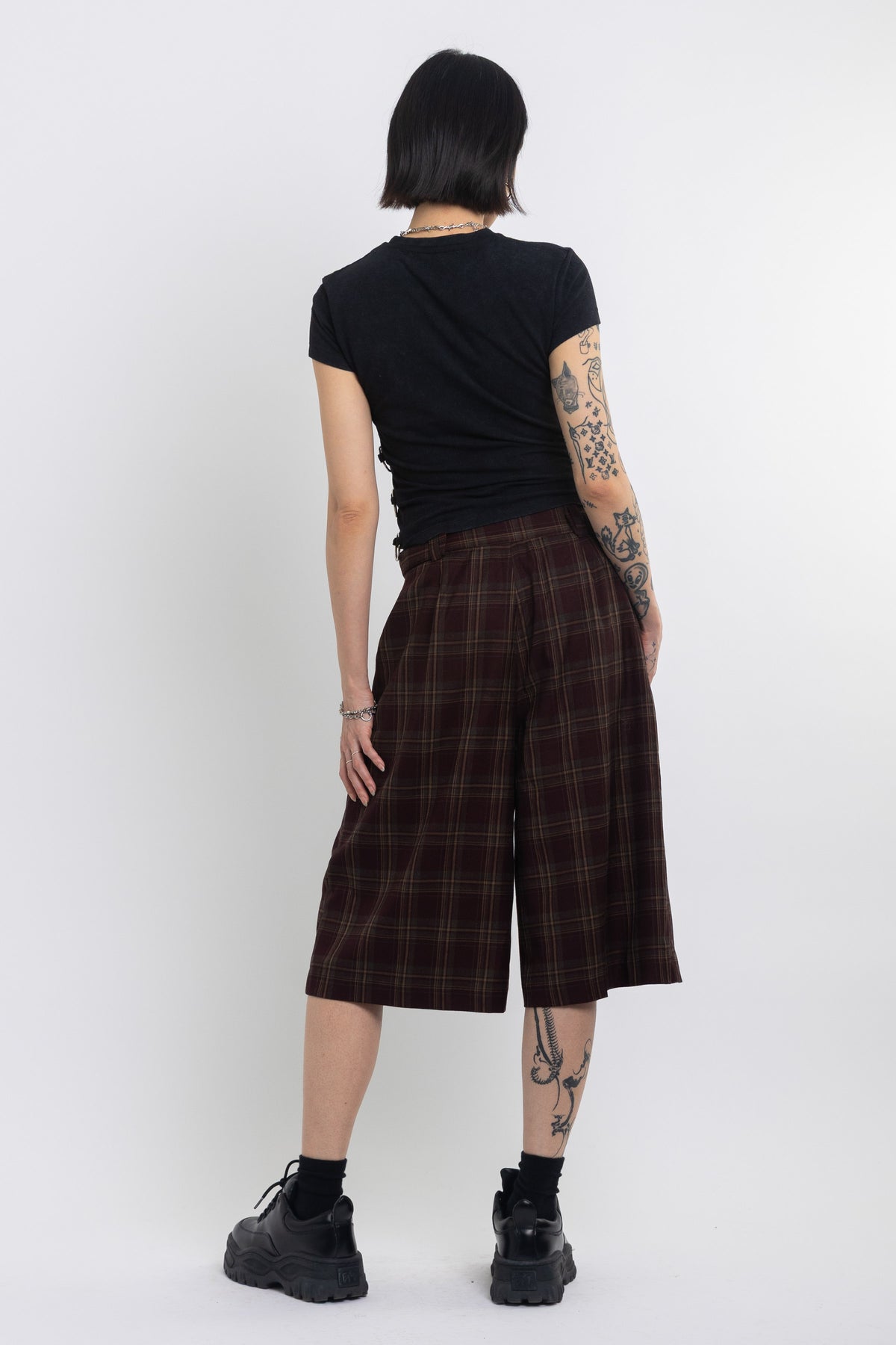 Burgundy check longline tailored shorts with silver D-ring hardware worn by model