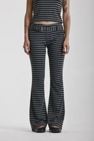 Grey and black stripe jersey flare trousers with eyelet belt, worn by model