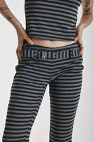 Grey and black stripe jersey flare trousers with eyelet belt, worn by model