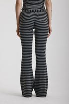 Grey and black stripe jersey flare trousers with eyelet belt, worn by model