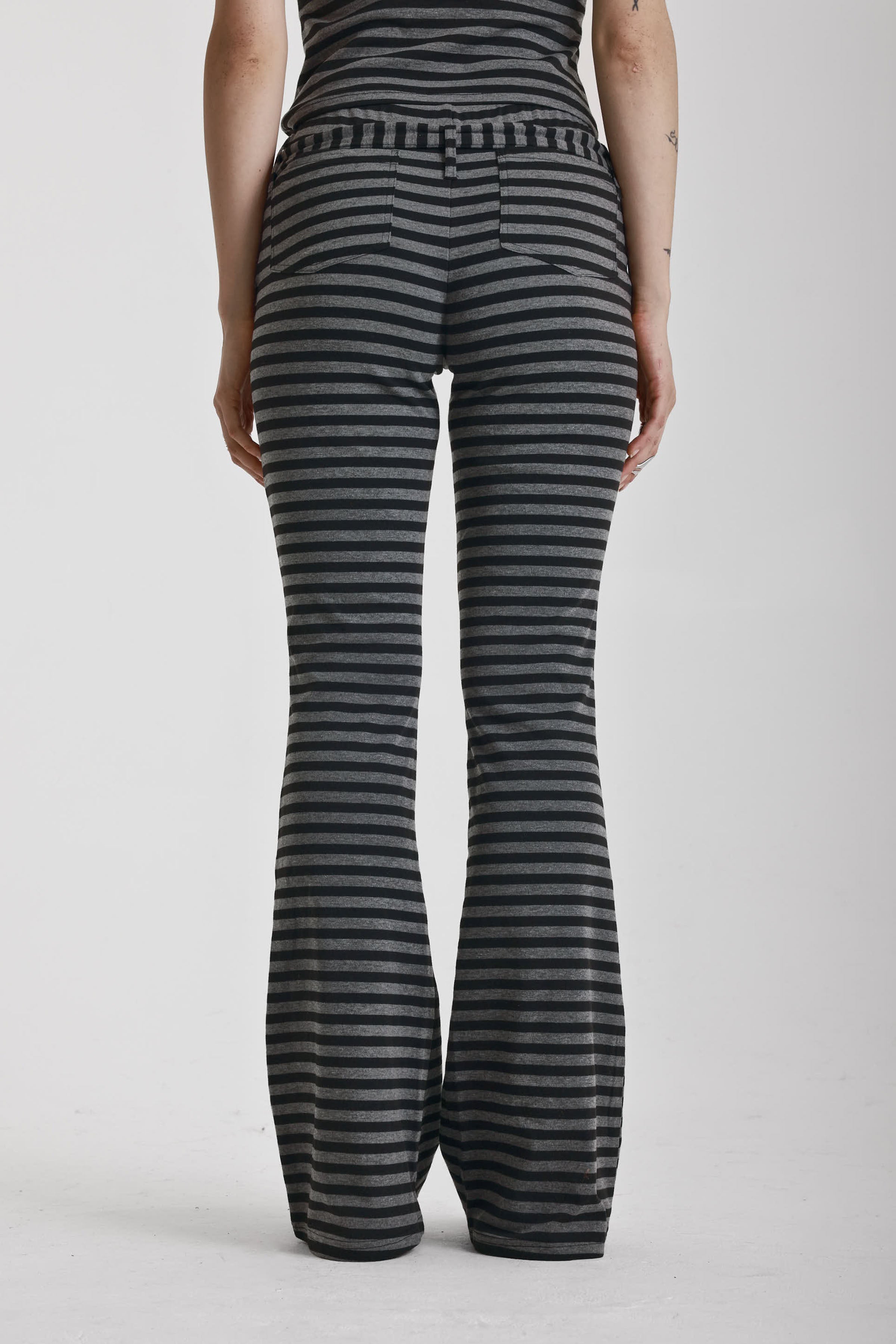 Grey and black stripe jersey flare trousers with eyelet belt, worn by model