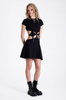 Little black mini dress with cut outs and eyelet detail buckle straps, worn by model