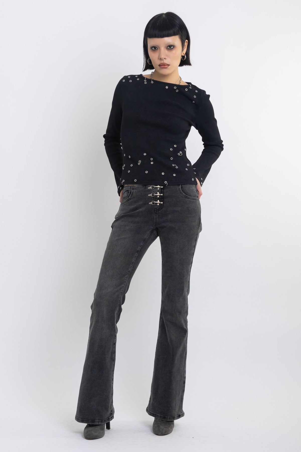 Washed black low rise flare jeans with no waistband and silver clasp hardware, worn by model