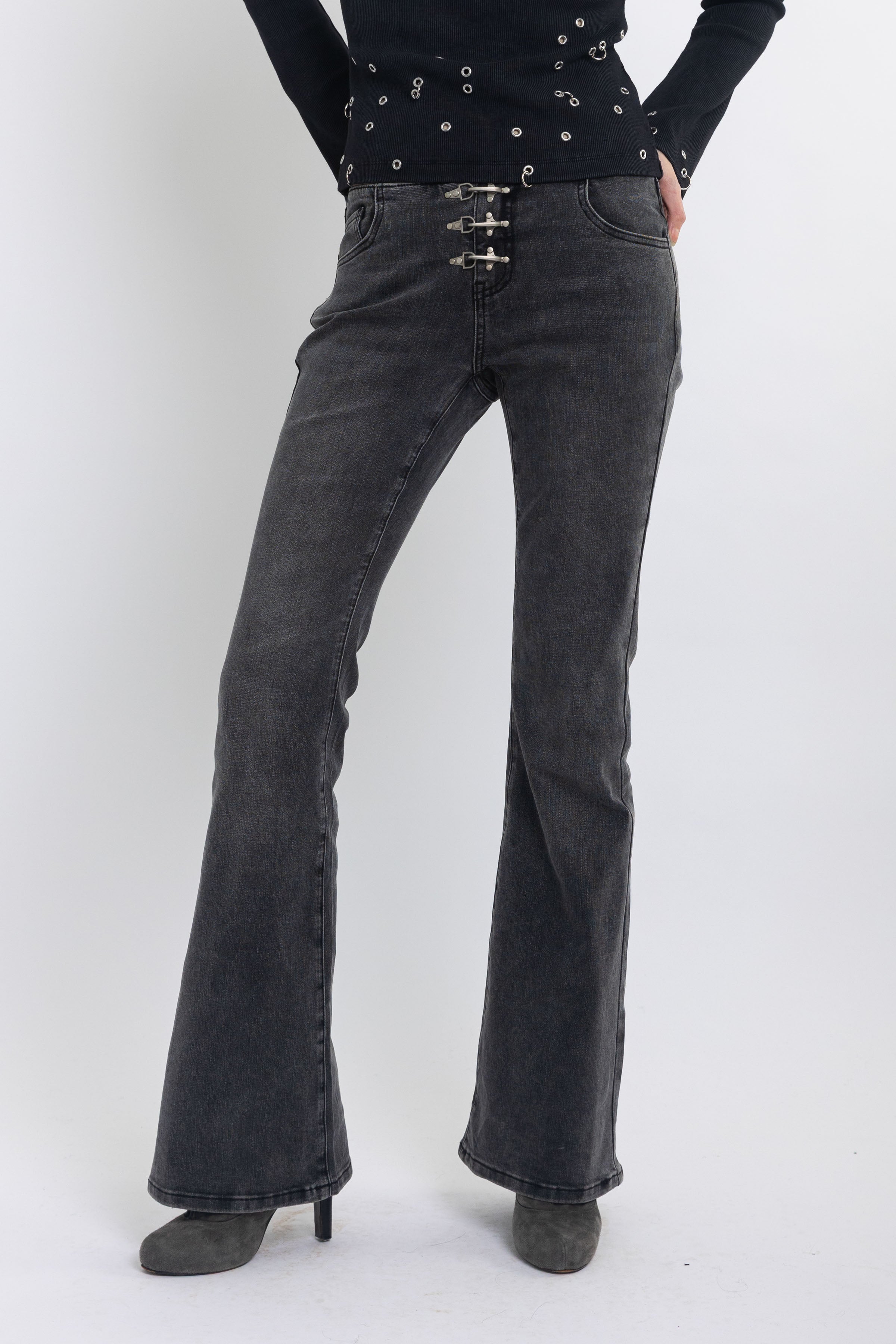 Washed black low rise flare jeans with no waistband and silver clasp hardware, worn by model