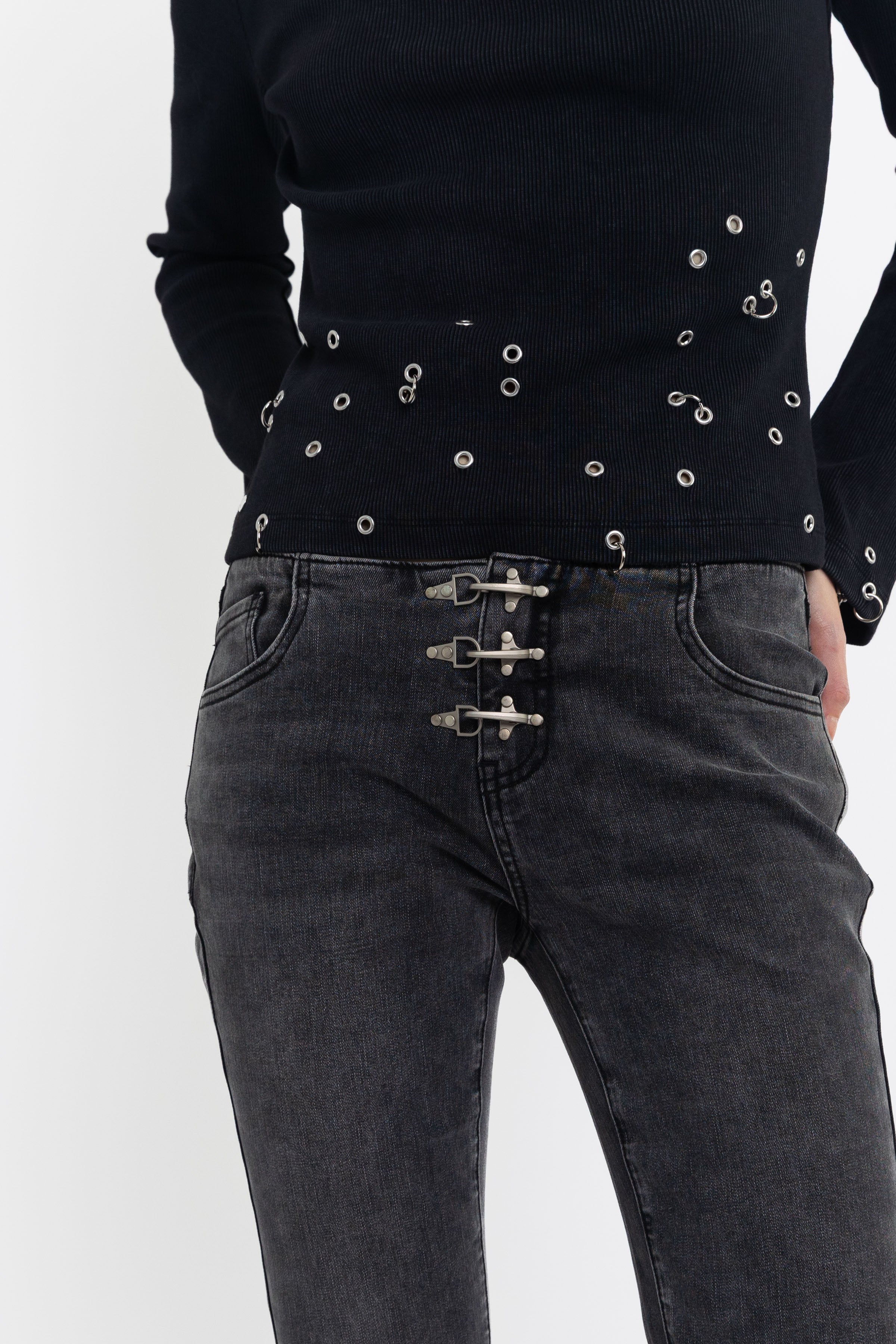 Washed black low rise flare jeans with no waistband and silver clasp hardware, worn by model