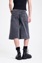 Washed black longline oversized denim jorts with no waistband and silver latch clasp detail, worn by model